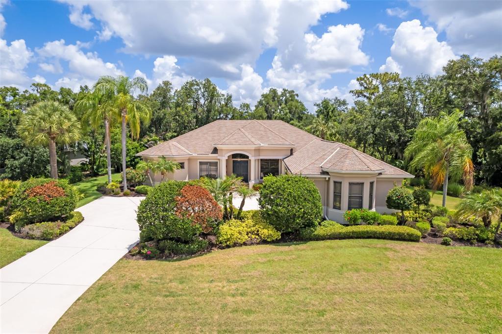 A single-story house with a tan exterior, a hip roof, and a landscaped front yard — 2339 LITTLE COUNTRY ROAD, PARRISH, FL