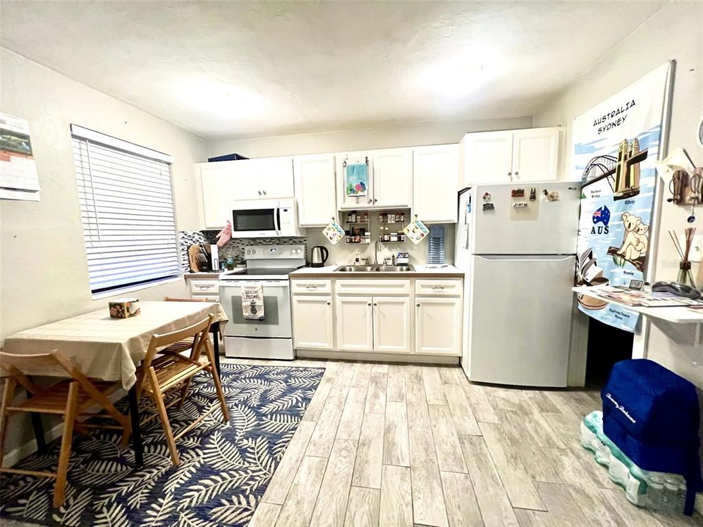 A kitchen features white cabinets, a white refrigerator, a dining table, and a patterned rug — 6802 GULF WINDS DRIVE, ST PETE BEACH, FL