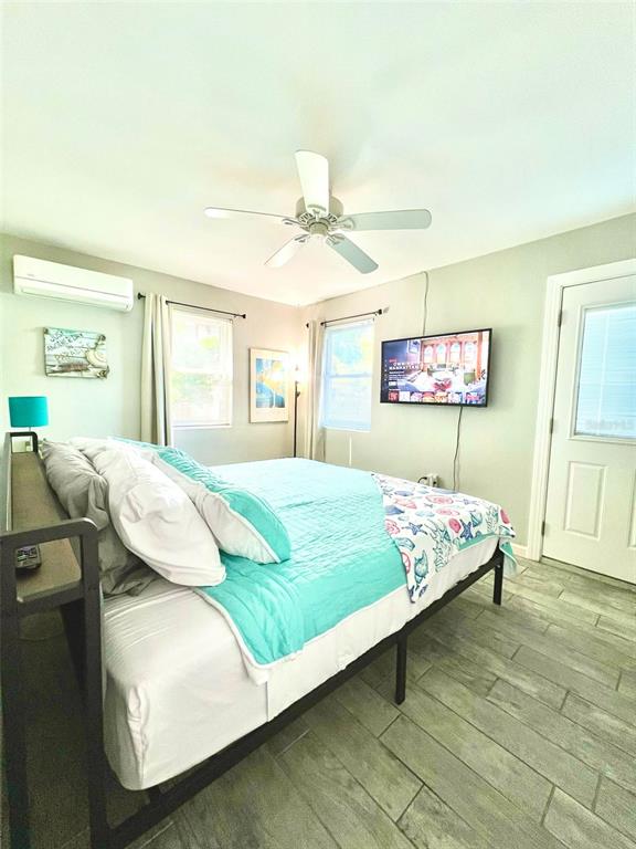 A bedroom features a bed with a turquoise quilt, a ceiling fan, and a television — 6802 GULF WINDS DRIVE, ST PETE BEACH, FL