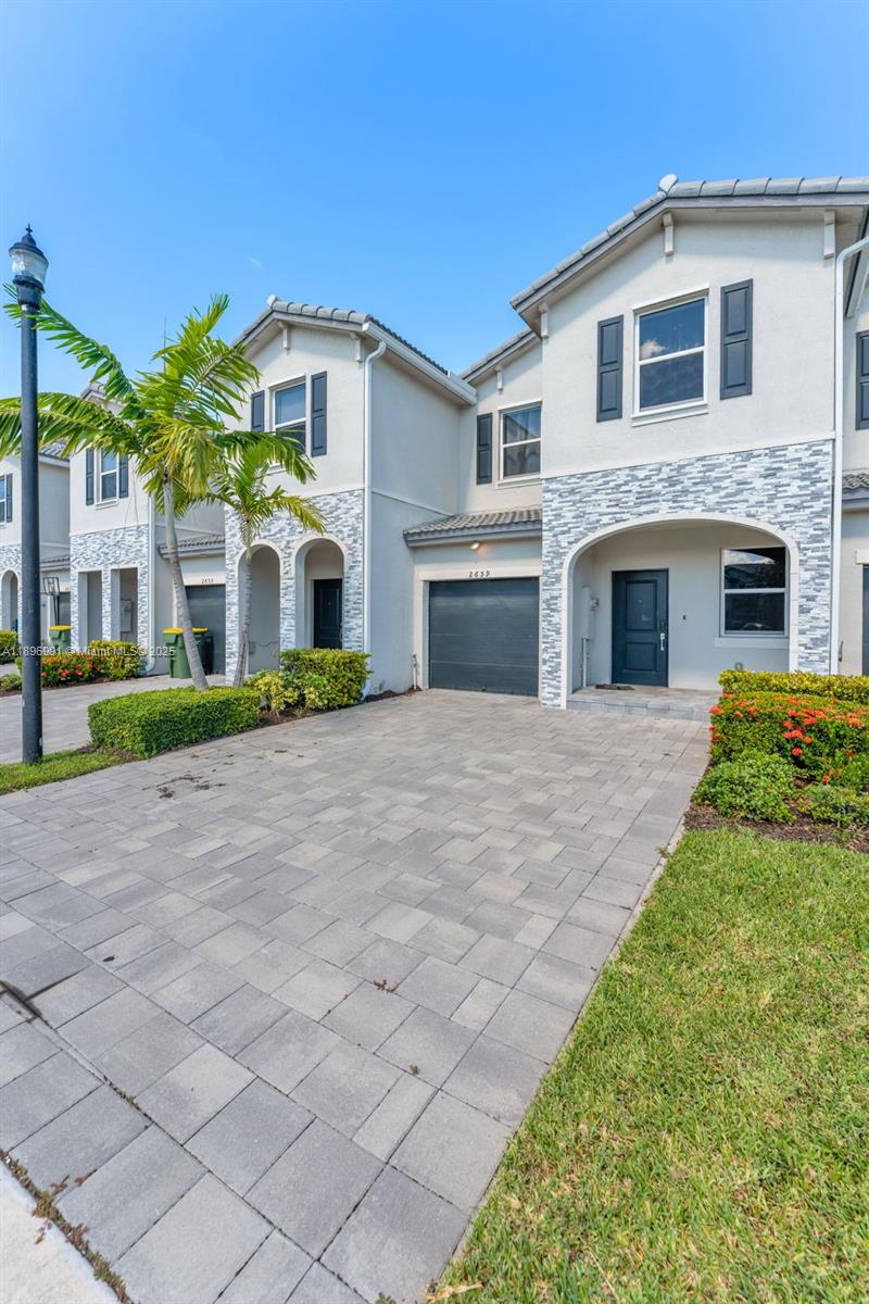 A two-story townhouse exterior features a stone-accented facade, a paved driveway, and a garage — 2659 SE 11th St, Homestead FL 33035, HOMESTEAD, FL