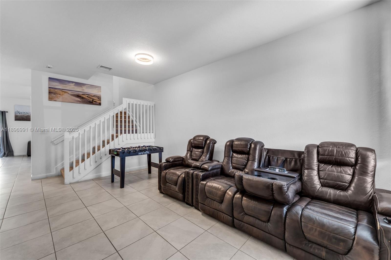 A living room features tile flooring, a staircase with white railings, and brown leather recliners — 2659 SE 11th St, Homestead FL 33035, HOMESTEAD, FL