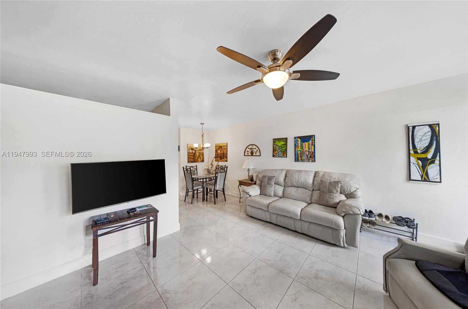 A living room features light tile flooring, a ceiling fan, a sofa, and a television — 15610 NE 6th Ave # 9B, Miami FL 33162, MIAMI, FL