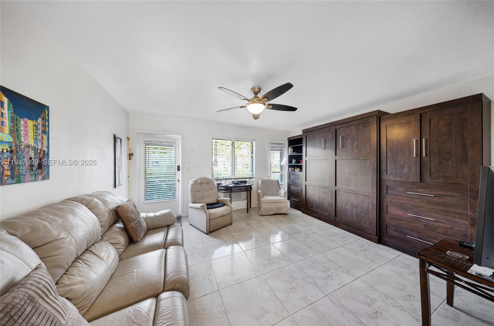 A living room features a large dark wood wall unit, light tile floors, and a sofa — 15610 NE 6th Ave # 9B, Miami FL 33162, MIAMI, FL
