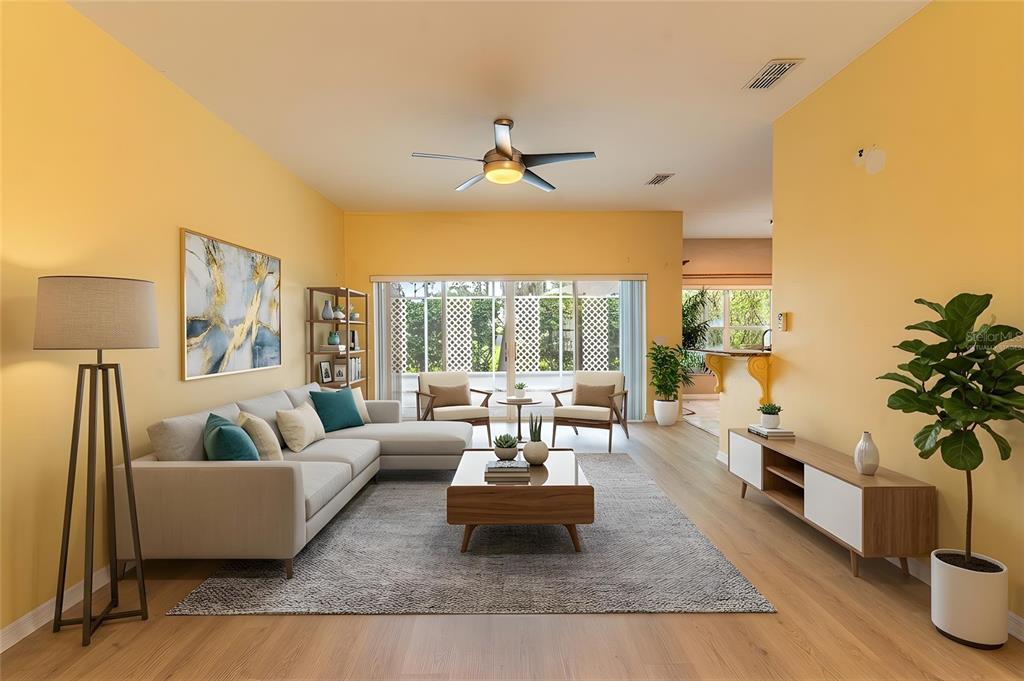 A living room with yellow walls, a sectional sofa, a coffee table, and wood flooring — 157 SAND PIPER DRIVE, KISSIMMEE, FL