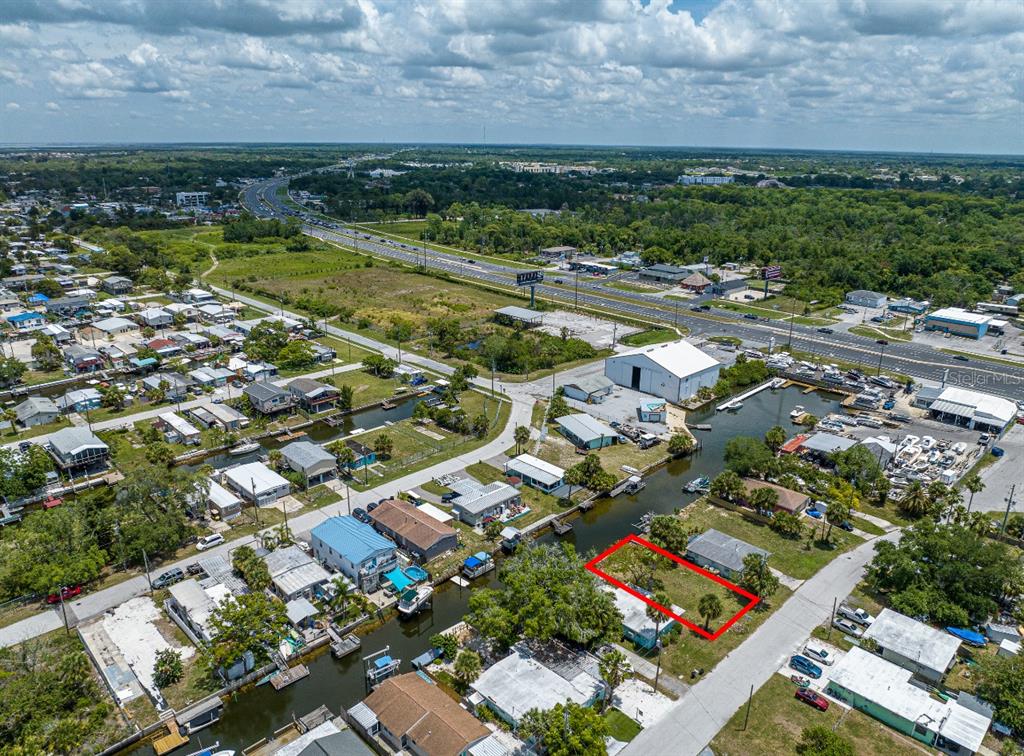 An aerial view shows a vacant rectangular lot outlined in red next to a canal — 6837 SANDERLING LANE, HUDSON, FL