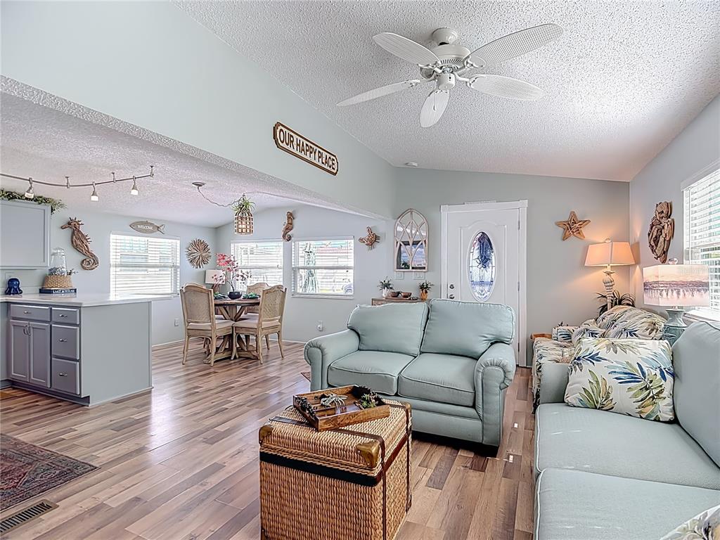 An open-concept living and dining area features light blue walls, wood-look flooring, and a ceiling fan — 9000 US HWY 192 # 537 UNIT 537, CLERMONT, FL