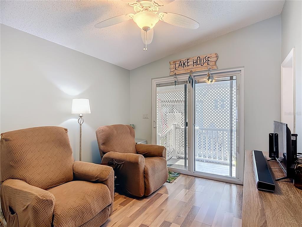 A living room features two brown recliners, wood flooring, a ceiling fan, and sliding glass doors — 9000 US HWY 192 # 537 UNIT 537, CLERMONT, FL