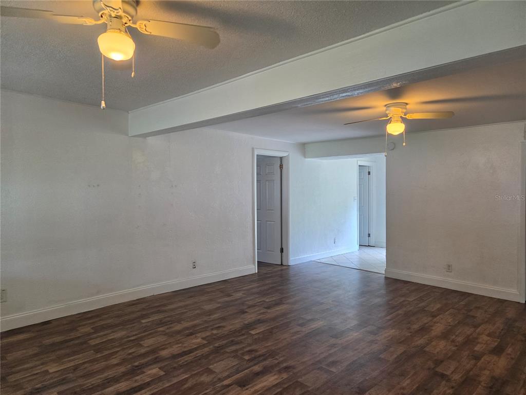 An interior room with white walls, wood-look flooring, and two ceiling fans — 769 GREENWAY PLACE, DAYTONA BEACH, FL