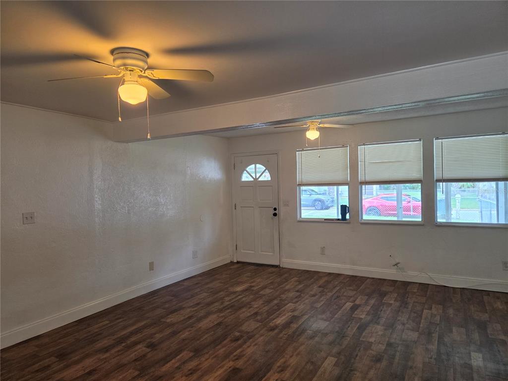A living room with wood-look flooring, white walls, two ceiling fans, and three windows — 769 GREENWAY PLACE, DAYTONA BEACH, FL