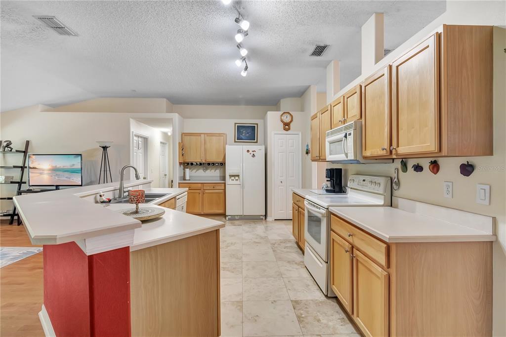 A kitchen with light wood cabinets, white countertops, tile flooring, and a breakfast bar — 1193 WINTERVILLE STREET, DELTONA, FL