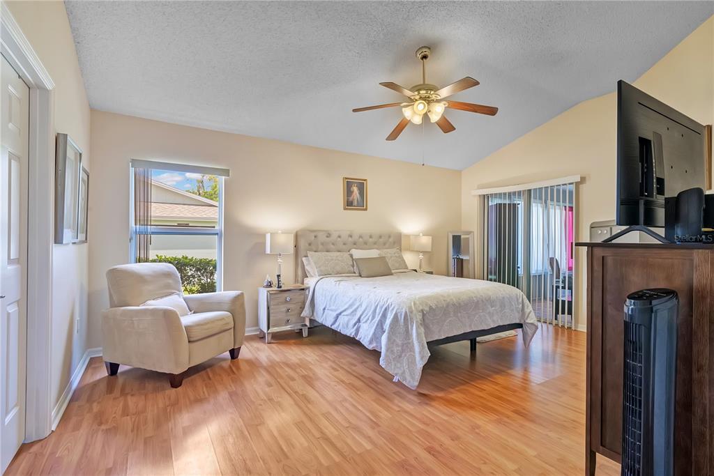 A bedroom features light wood flooring, a tufted headboard, a ceiling fan, and a window — 1193 WINTERVILLE STREET, DELTONA, FL