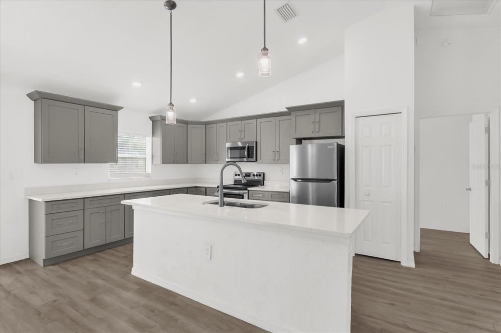 A kitchen features gray cabinets, white countertops, a central island, and stainless steel appliances — 14923 SW 66TH AVENUE ROAD, OCALA, FL