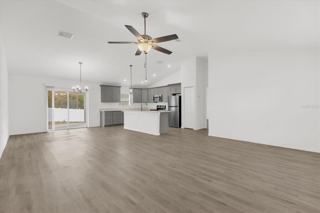 An open-concept living area features a kitchen with gray cabinets, a white island, and flooring — 14923 SW 66TH AVENUE ROAD, OCALA, FL