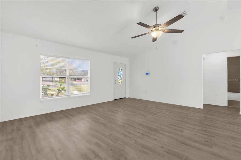 A living room with white walls, wood-look flooring, a ceiling fan, and a front door — 14923 SW 66TH AVENUE ROAD, OCALA, FL
