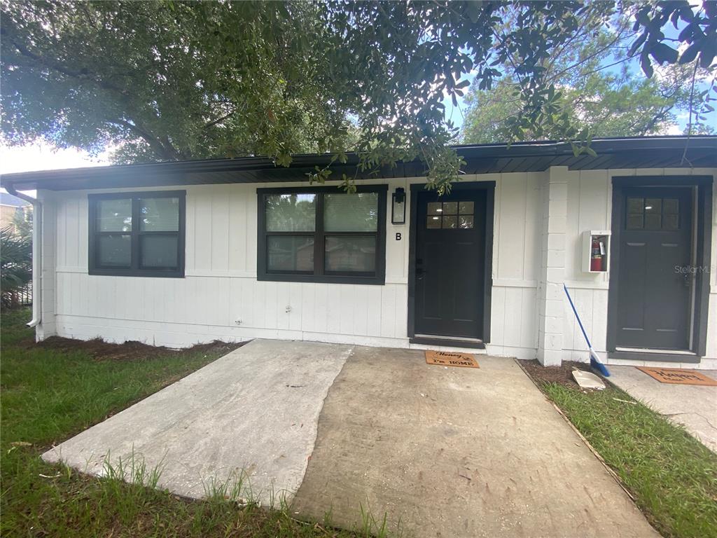 The exterior of a white, single-story building features two dark doors and concrete entryways — 704 ANGELINA LANE UNIT B, LAKELAND, FL