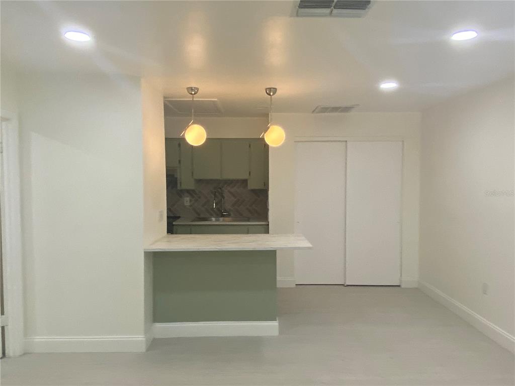 A kitchen with a breakfast bar, light green cabinets, and pendant lighting opens to a room — 704 ANGELINA LANE UNIT B, LAKELAND, FL