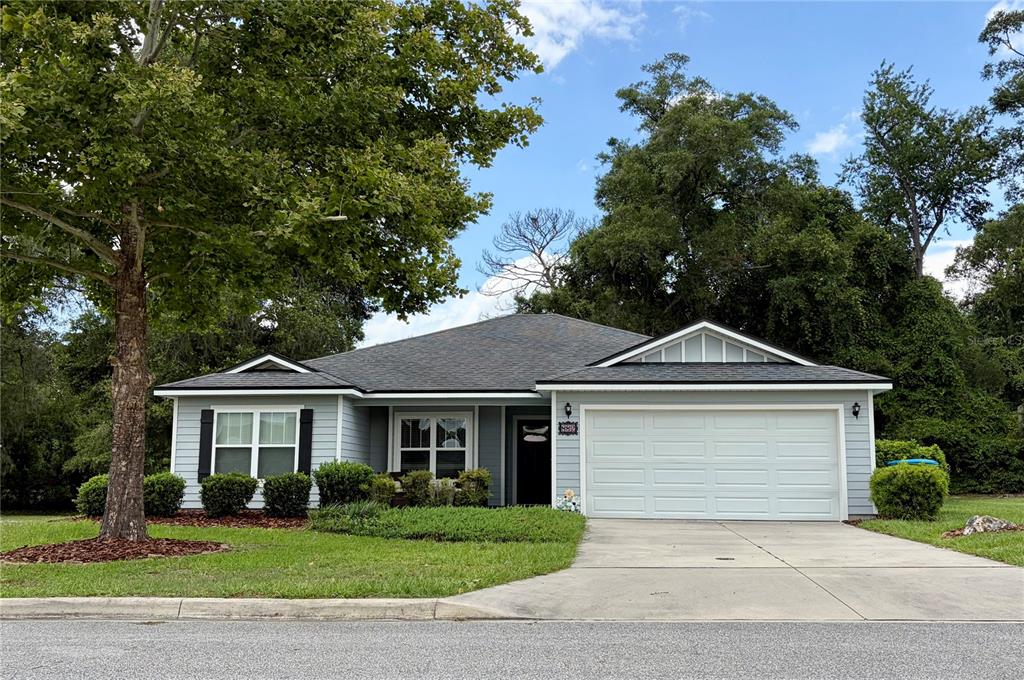 A single-story house with light blue siding, a white garage door, and a front lawn — 882 NW 256TH WAY, NEWBERRY, FL