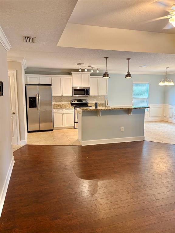 A kitchen with white cabinets, stainless steel appliances, and a breakfast bar overlooks a dining area — 882 NW 256TH WAY, NEWBERRY, FL