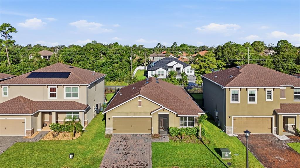 An aerial view shows three suburban houses with brown roofs and paved driveways — 895 LAZIO CIRCLE, DEBARY, FL