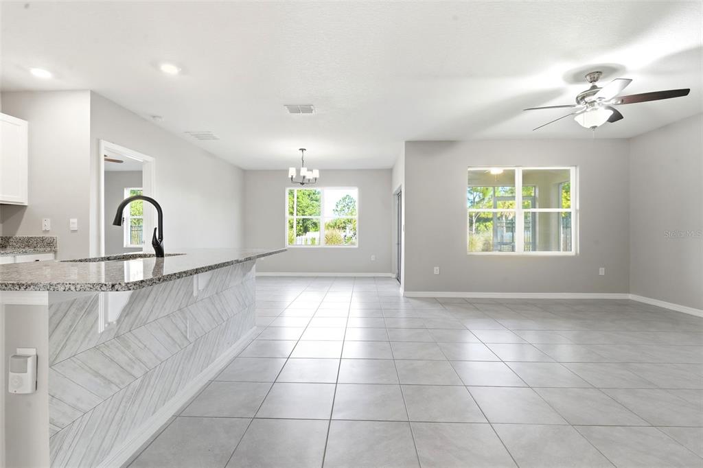 An open-concept kitchen and living area features light gray tile flooring and neutral walls — 895 LAZIO CIRCLE, DEBARY, FL