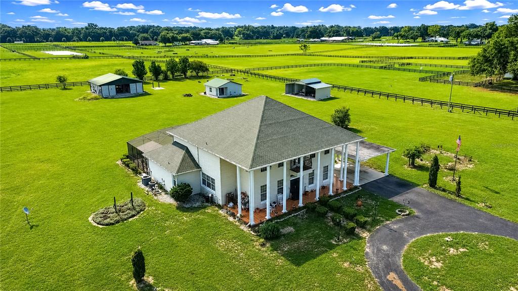 An aerial view shows a two-story house with a wrap-around porch on a large farm — 12345 NE 14TH AVENUE, ANTHONY, FL