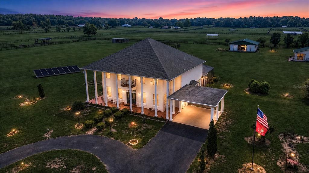 An aerial view shows a two-story white house with a wraparound porch and carport — 12345 NE 14TH AVENUE, ANTHONY, FL