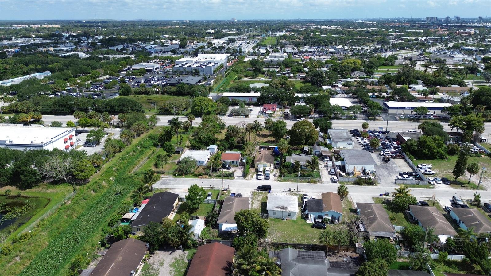 An aerial view shows a residential neighborhood with houses, trees, and nearby commercial buildings — 2944 Westgate Avenue, West Palm Beach FL 33409, WEST PALM BEACH, FL