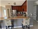 A kitchen features dark wood cabinets, stainless steel appliances, and a breakfast bar with chairs — 1403 KISSIMMEE COURT, POINCIANA, FL