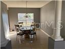 A dining area features a round glass table with four chairs and a hanging light — 1403 KISSIMMEE COURT, POINCIANA, FL