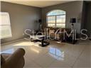A living room features light-colored tile flooring, a brown sofa, and an arched window — 1403 KISSIMMEE COURT, POINCIANA, FL