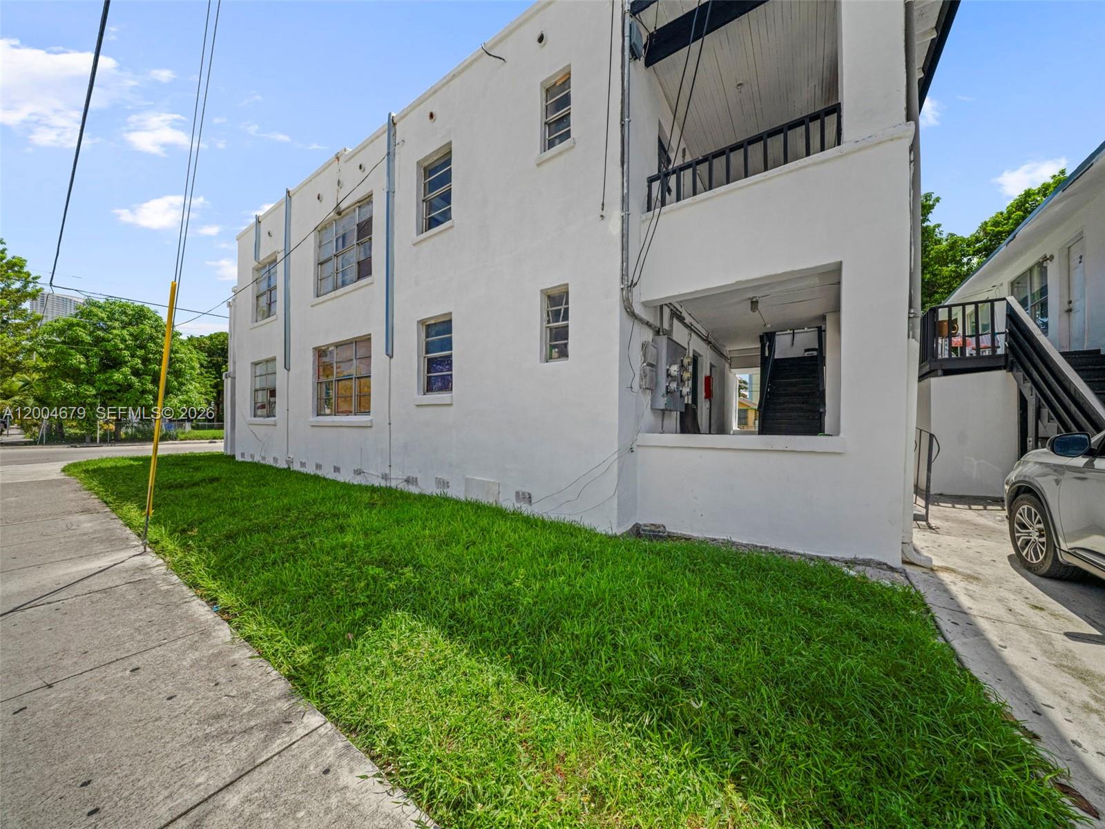 A white multi-story apartment building exterior features a grassy lawn and an outdoor staircase — 500 SW 8th AVE, Miami FL 33130, MIAMI, FL
