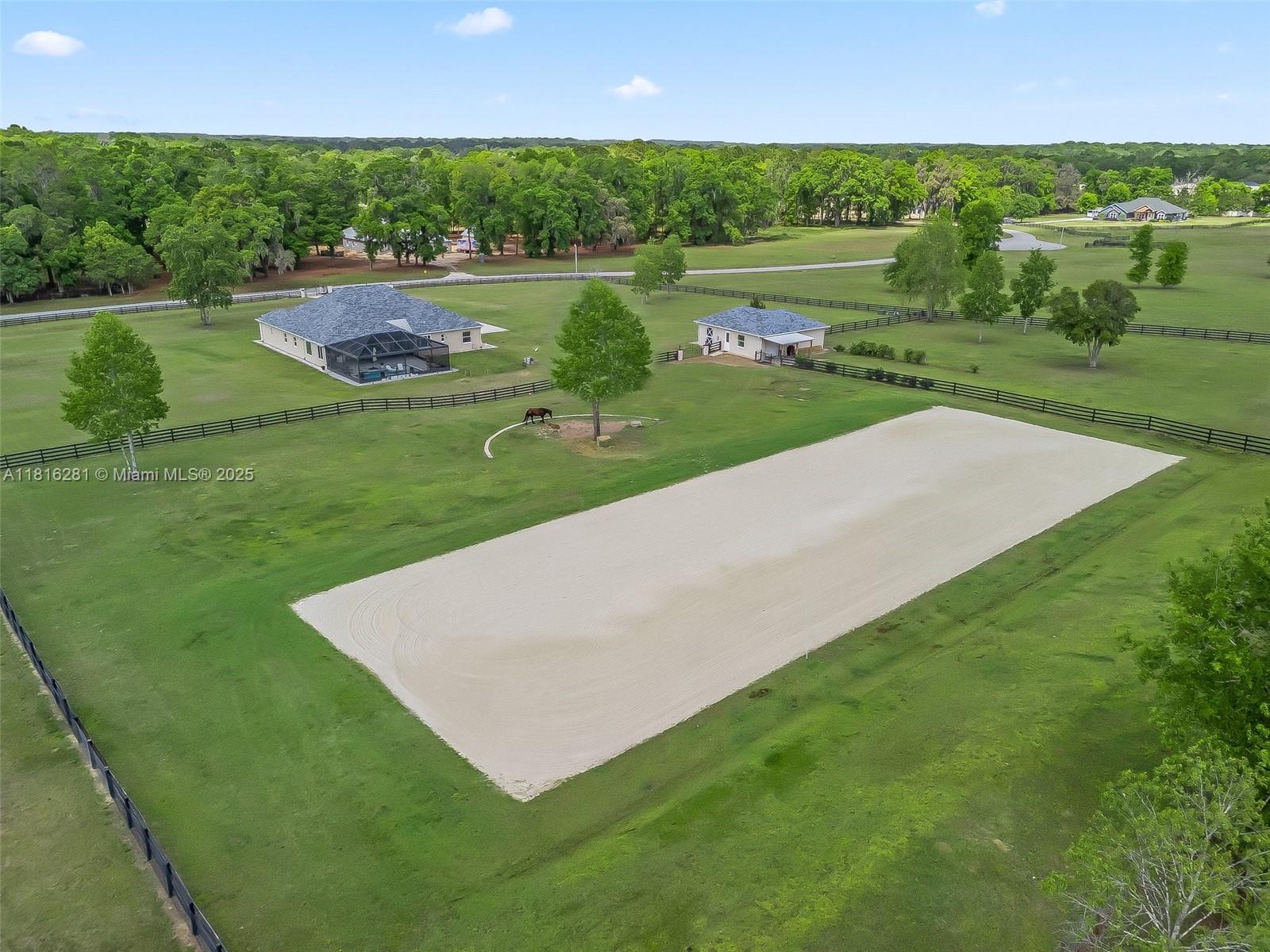An aerial view shows a large sandy riding arena, a house, and a detached building — 7161 NE 22nd Ct Rd, Ocala FL 34479, OCALA, FL