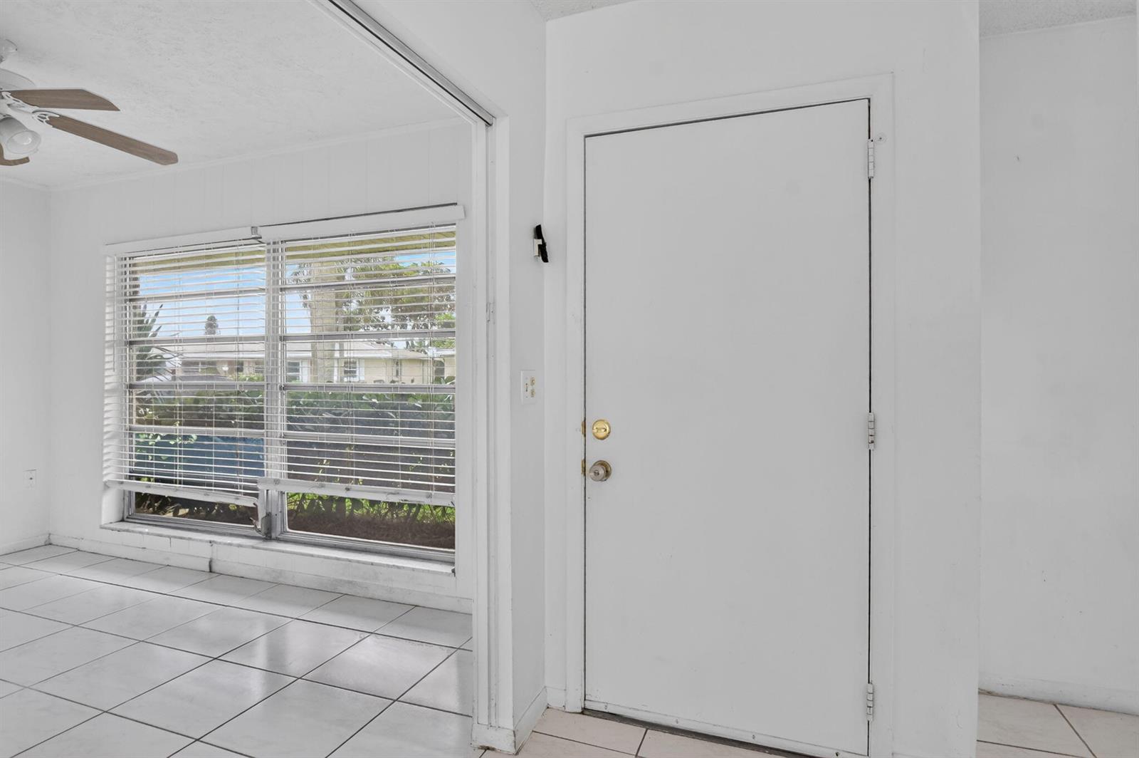 A white door stands next to a large window with blinds in a tiled room — 20923 Sedgewick Drive # 386, Boca Raton FL 33433, BOCA RATON, FL