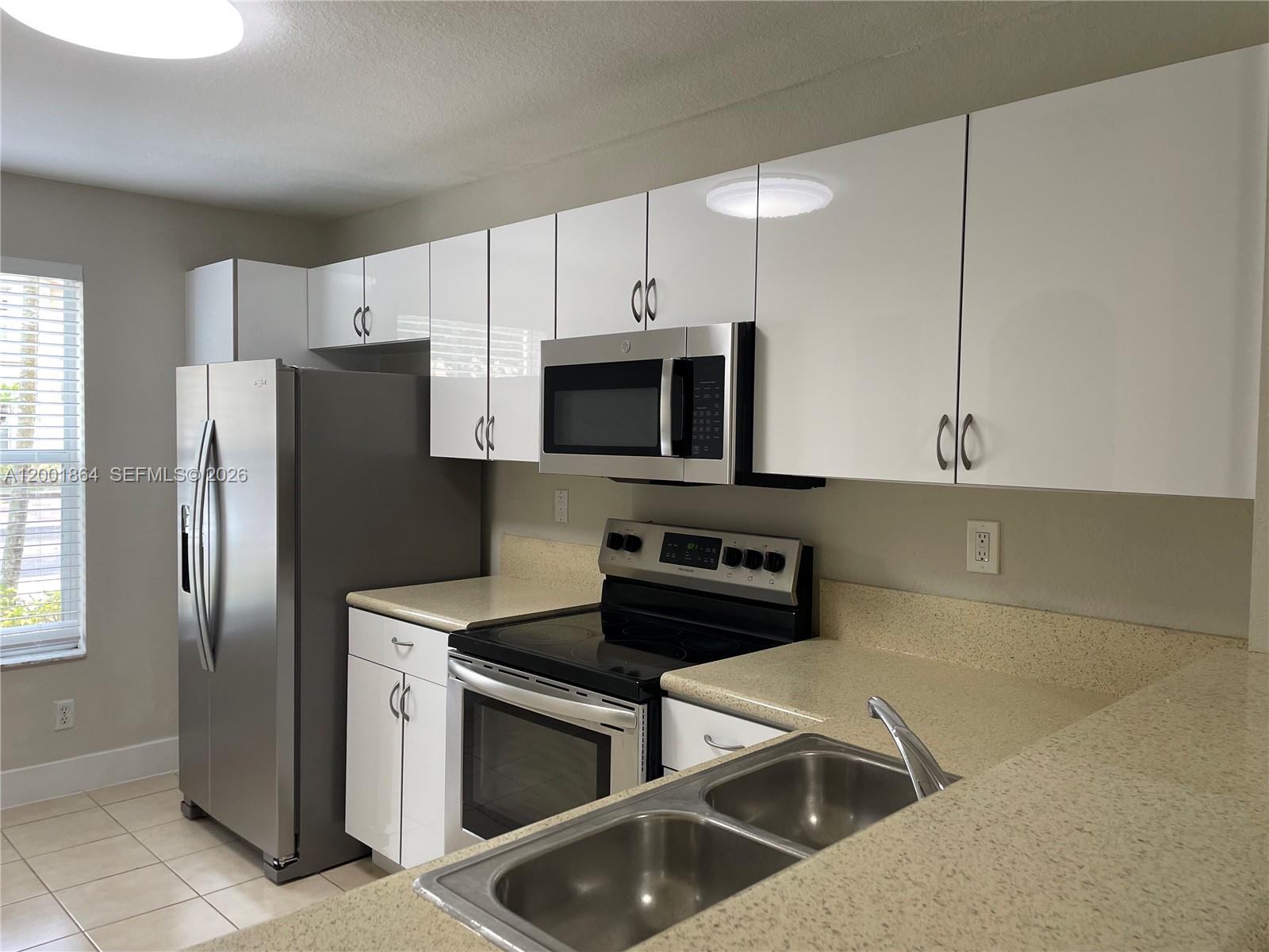 A kitchen features white cabinets, stainless steel appliances, and beige speckled countertops — 12957 SW 30th Ct # 141, Miramar FL 33027, MIRAMAR, FL