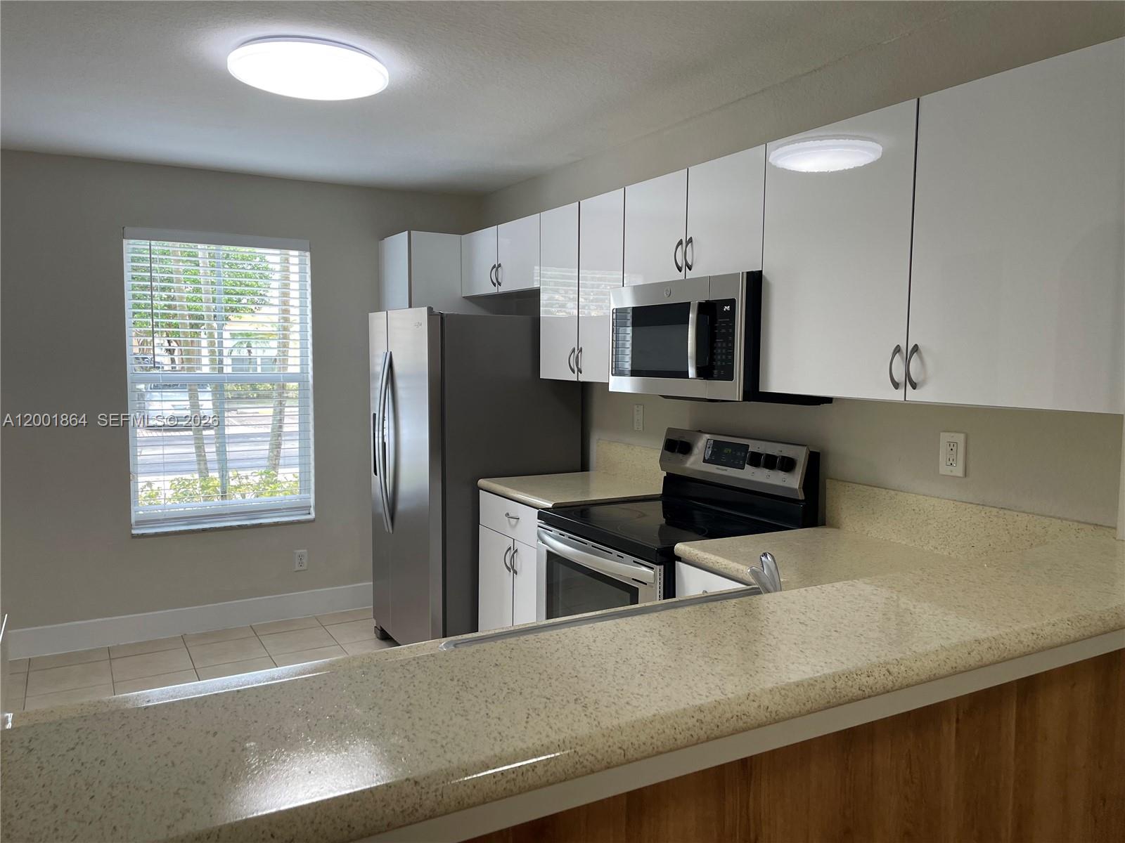 A kitchen features white cabinets, stainless steel appliances, and beige speckled countertops — 12957 SW 30th Ct # 141, Miramar FL 33027, MIRAMAR, FL