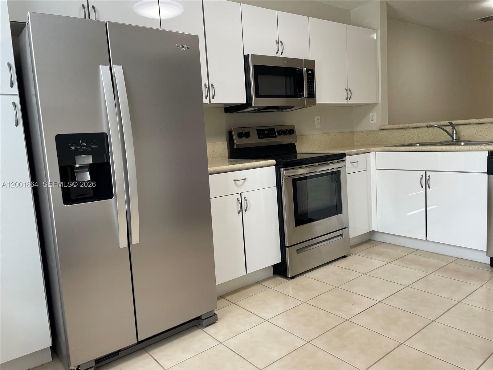 A kitchen features white cabinets, stainless steel appliances, and light-colored countertops and tile flooring — 12957 SW 30th Ct # 141, Miramar FL 33027, MIRAMAR, FL