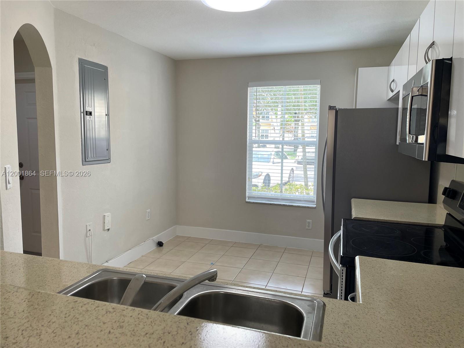 A kitchen features a double sink, stainless steel appliances, tile flooring, and a window — 12957 SW 30th Ct # 141, Miramar FL 33027, MIRAMAR, FL
