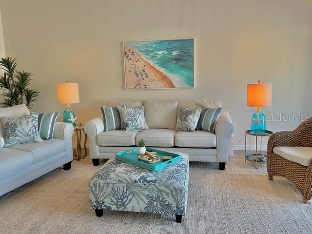 A living room features a sofa, loveseat, patterned ottoman, and coastal-themed decor — 6527 HAMLET DRIVE UNIT 26-A, ENGLEWOOD, FL