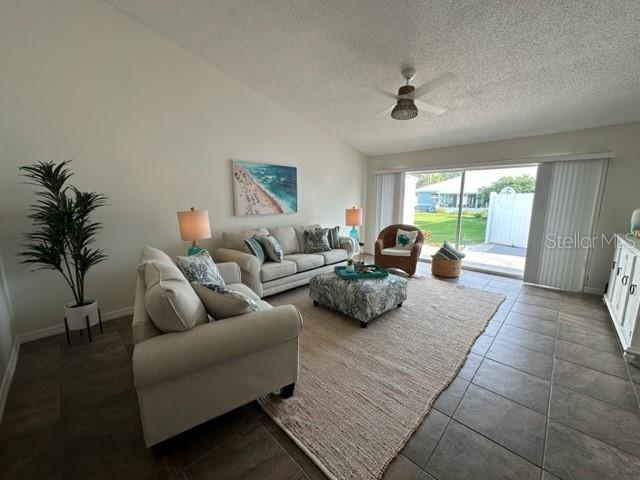 A living room features a beige sofa, patterned ottoman, and sliding glass doors to outdoors — 6527 HAMLET DRIVE UNIT 26-A, ENGLEWOOD, FL