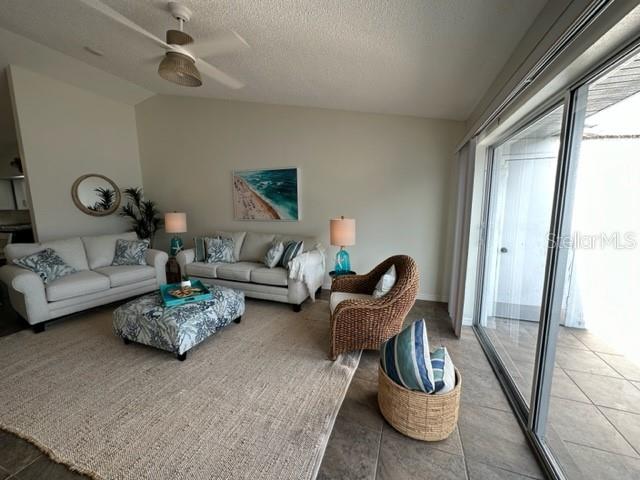 A living room features a white sofa, a patterned ottoman, and a wicker armchair — 6527 HAMLET DRIVE UNIT 26-A, ENGLEWOOD, FL