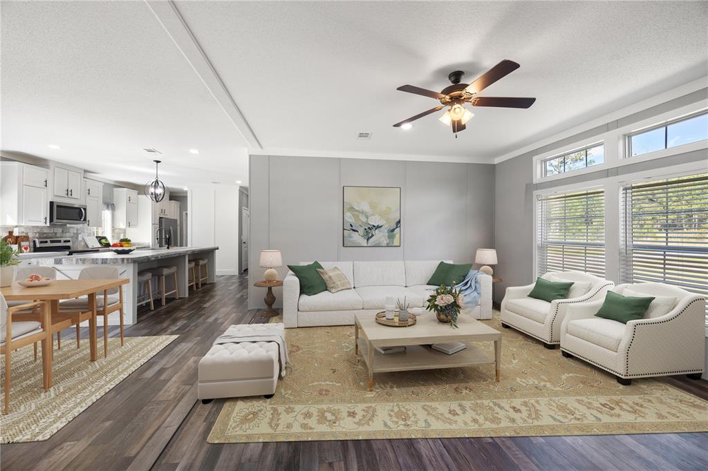 This open-concept living room features a white sofa, two armchairs, and a kitchen island — 2362 NE COUNTY ROAD 1469, HAWTHORNE, FL