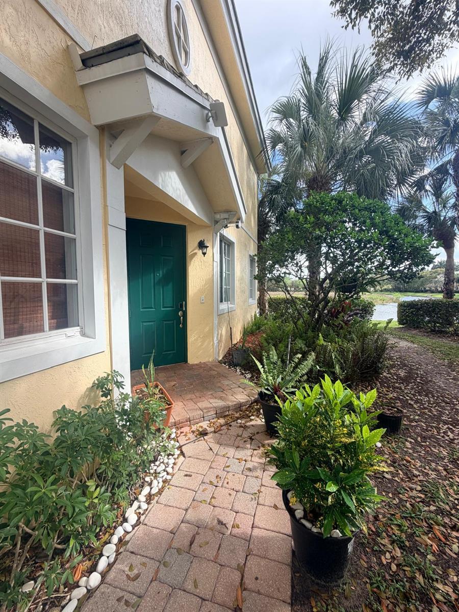 A paved walkway leads to the green front door of a yellow stucco house — 7644 Foxcroft Lane # 7644, Davie FL 33328, DAVIE, FL