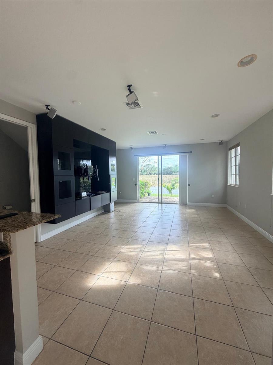 A living room features large beige floor tiles, a black built-in media unit, and sliding doors — 7644 Foxcroft Lane # 7644, Davie FL 33328, DAVIE, FL