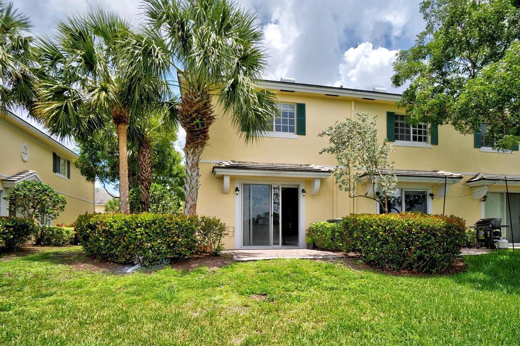 The exterior of a yellow two-story townhouse features a sliding glass door and palm trees — 7644 Foxcroft Lane # 7644, Davie FL 33328, DAVIE, FL