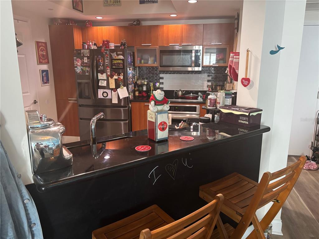 A kitchen features dark cabinetry, black countertops, a breakfast bar, and stainless steel appliances — 241 RIVERSIDE DRIVE UNIT 2308, HOLLY HILL, FL