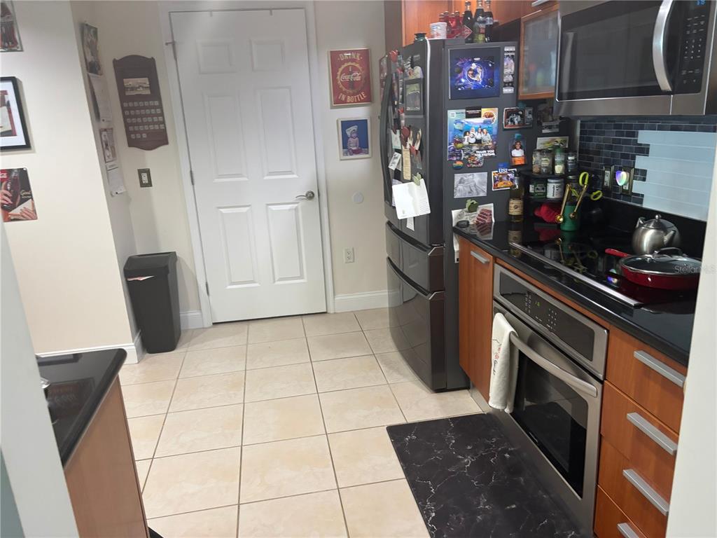 A kitchen features tile flooring, stainless steel appliances, wood cabinets, and a black backsplash — 241 RIVERSIDE DRIVE UNIT 2308, HOLLY HILL, FL