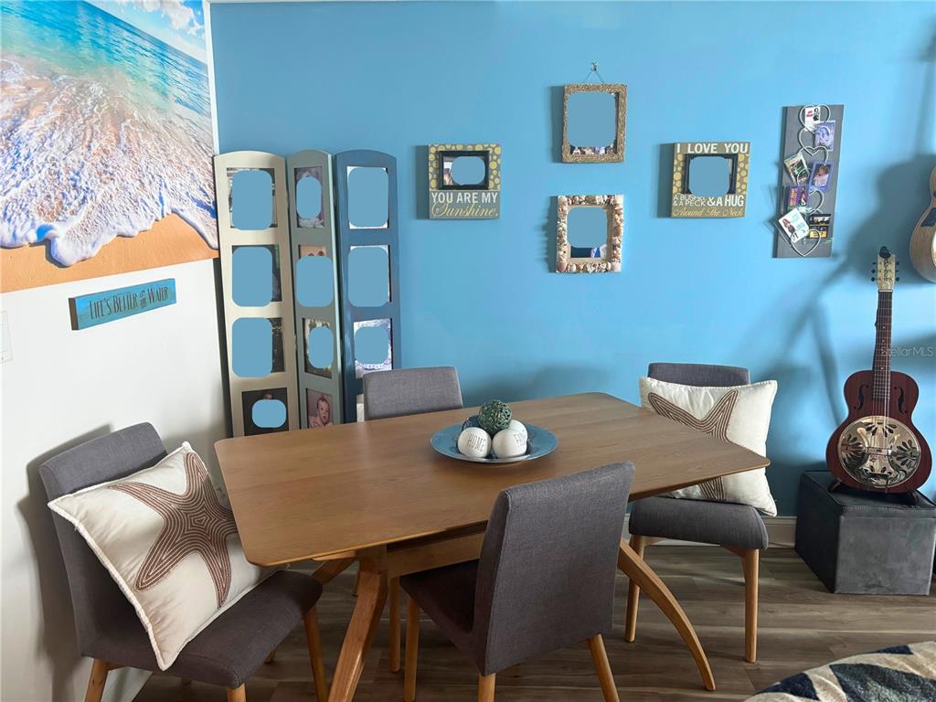 A dining area features a wooden table, four gray chairs, and blue walls with decor — 241 RIVERSIDE DRIVE UNIT 2308, HOLLY HILL, FL