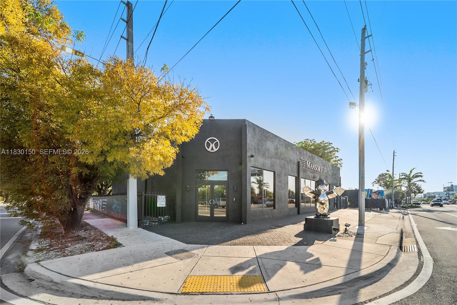 A black commercial building features a Mansory sign and a metallic statue on a corner lot — 100 NW 36th St, Miami FL 33127, MIAMI, FL