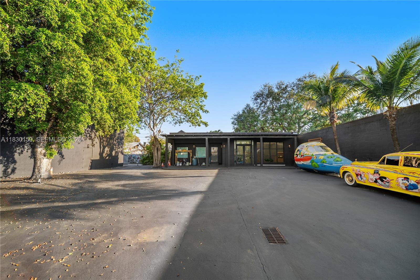 A dark-painted commercial building features a large parking lot with a decorated vintage car — 100 NW 36th St, Miami FL 33127, MIAMI, FL