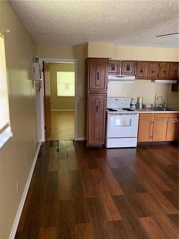 A kitchen with dark wood cabinets, a white stove, and wood-look flooring — 5217 17TH STREET, ZEPHYRHILLS, FL